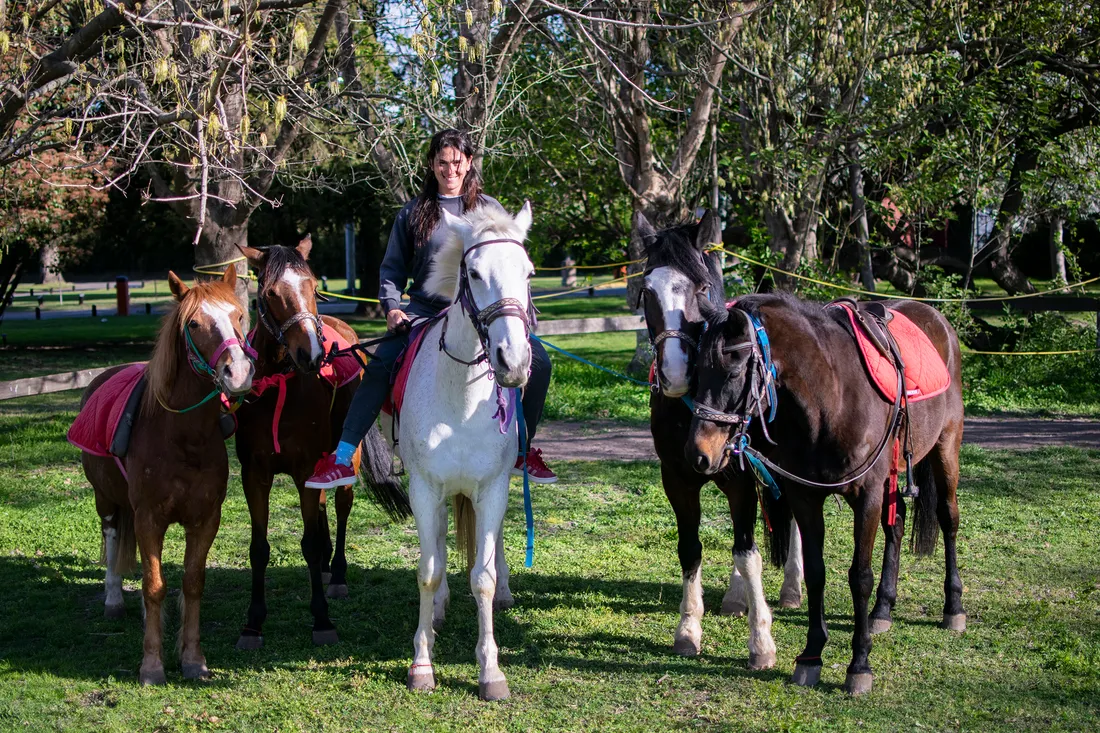 Los cinco caballos de Alaia, ensillados, junto a una integrante del equipo en el predio