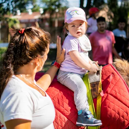 Una nena pequeña a caballo, sostenida por su profesional