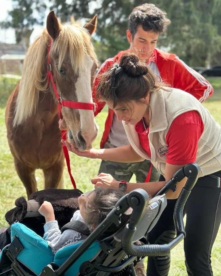 Una profesional acerca uno de los caballos a una paciente, junto a un asistente ecuestre